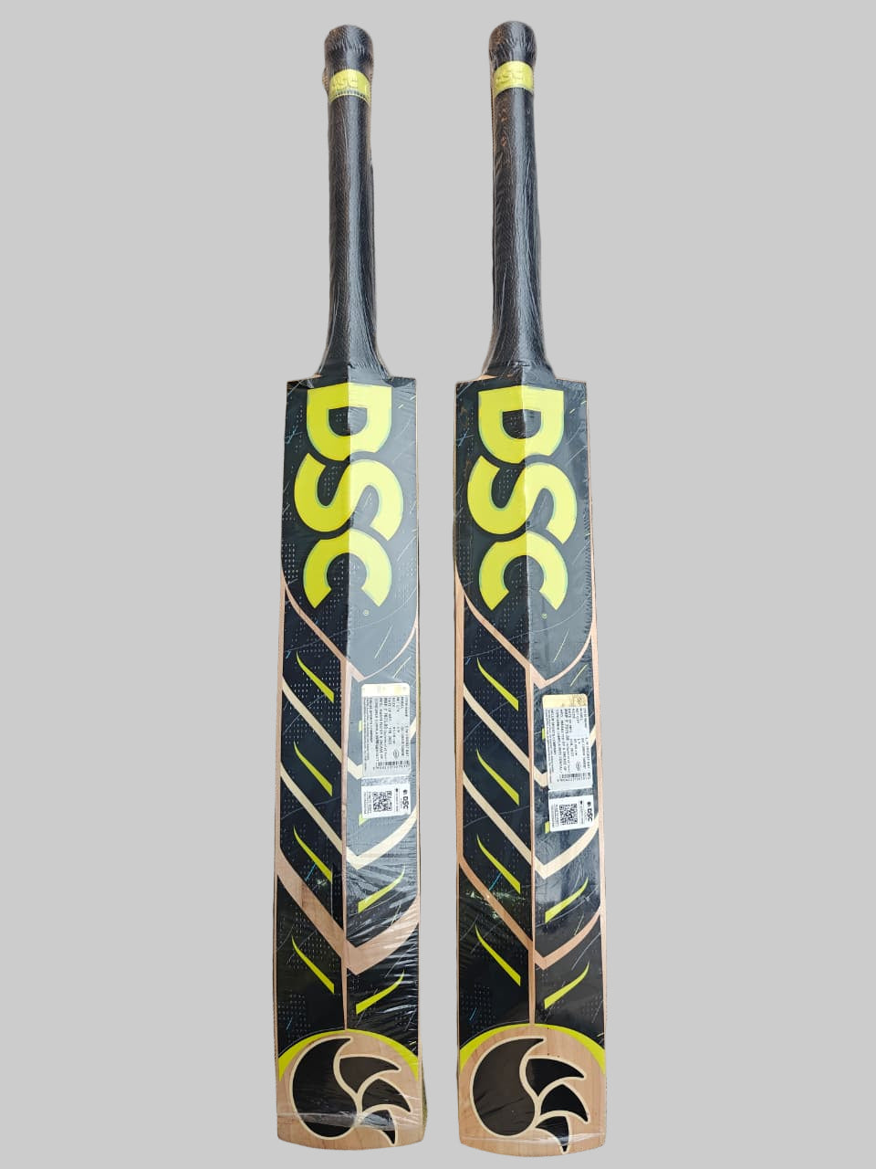 Two DSC cricket bats on a hexagonal patterned floor.